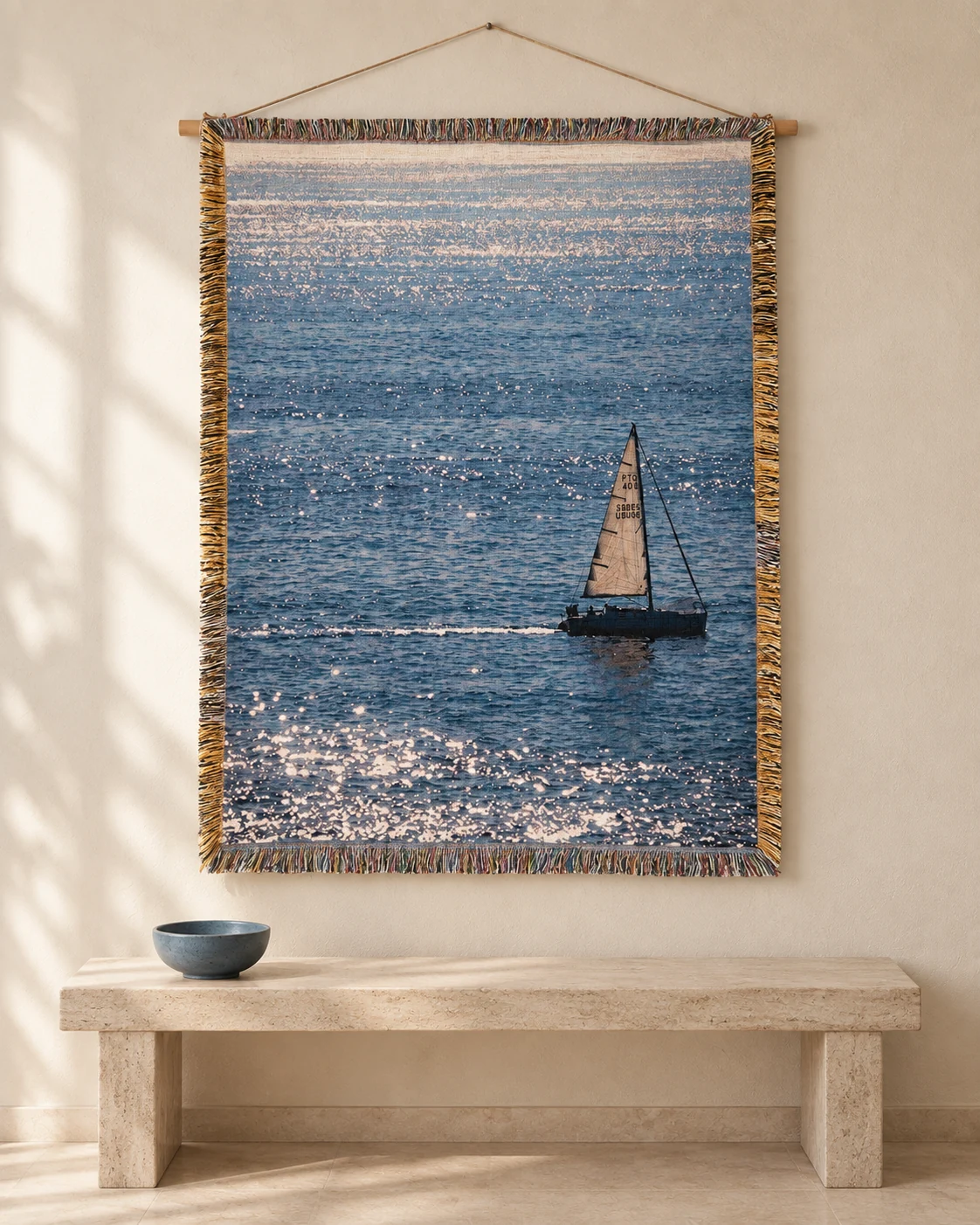 A sailboat on a shimmering blue sea tapestry above a pale stone console