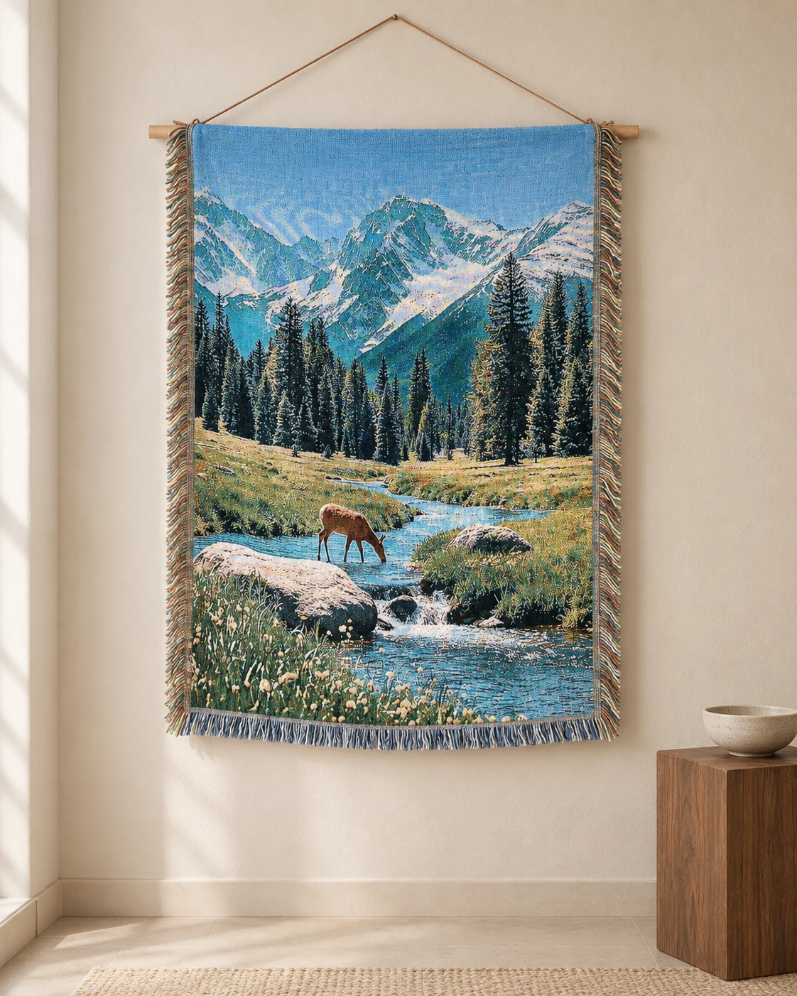 A deer drinking in an alpine stream beneath snowy mountains on a hanging tapestry