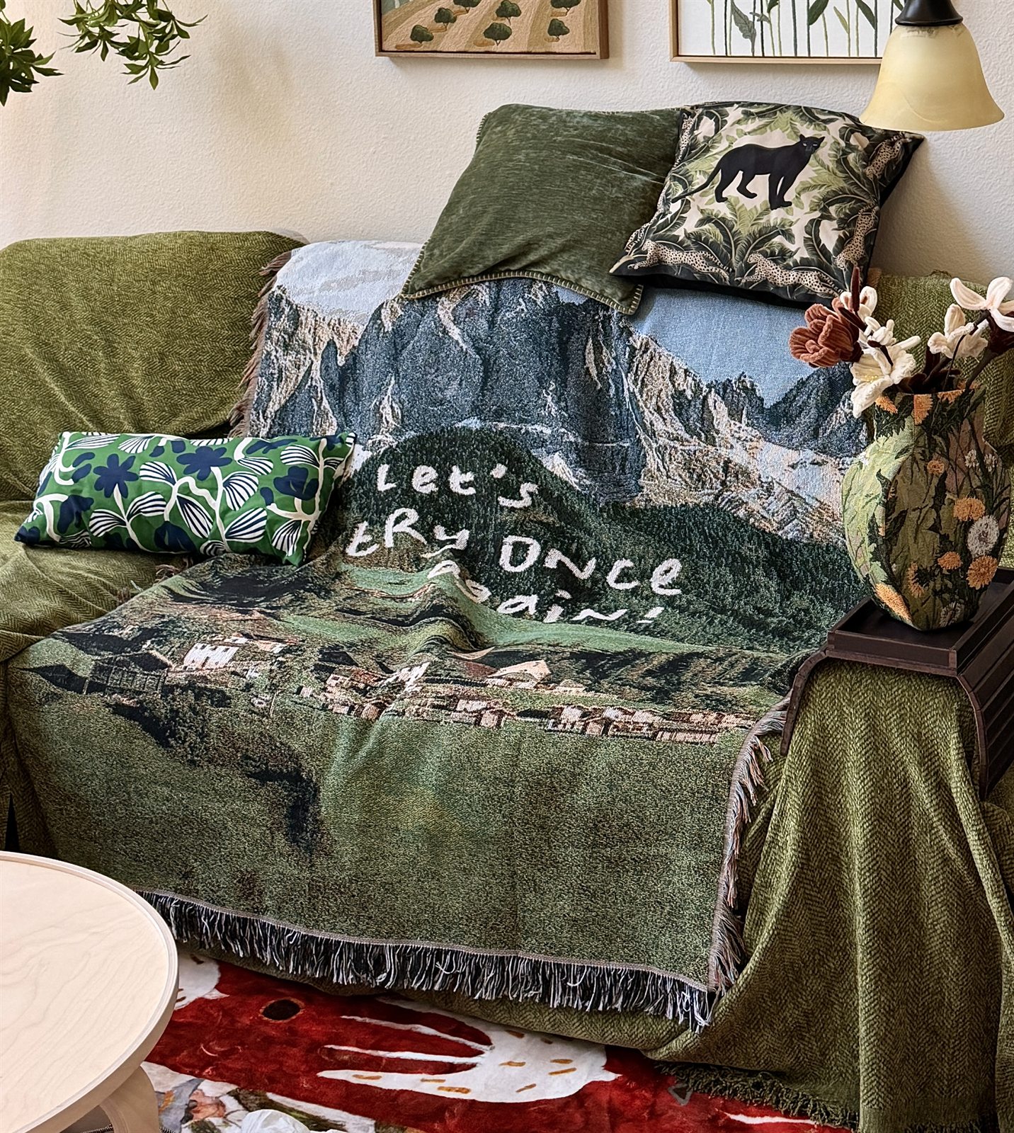 Green sofa layered with patterned Loomoria textiles, pillows and small objects in a warm living room