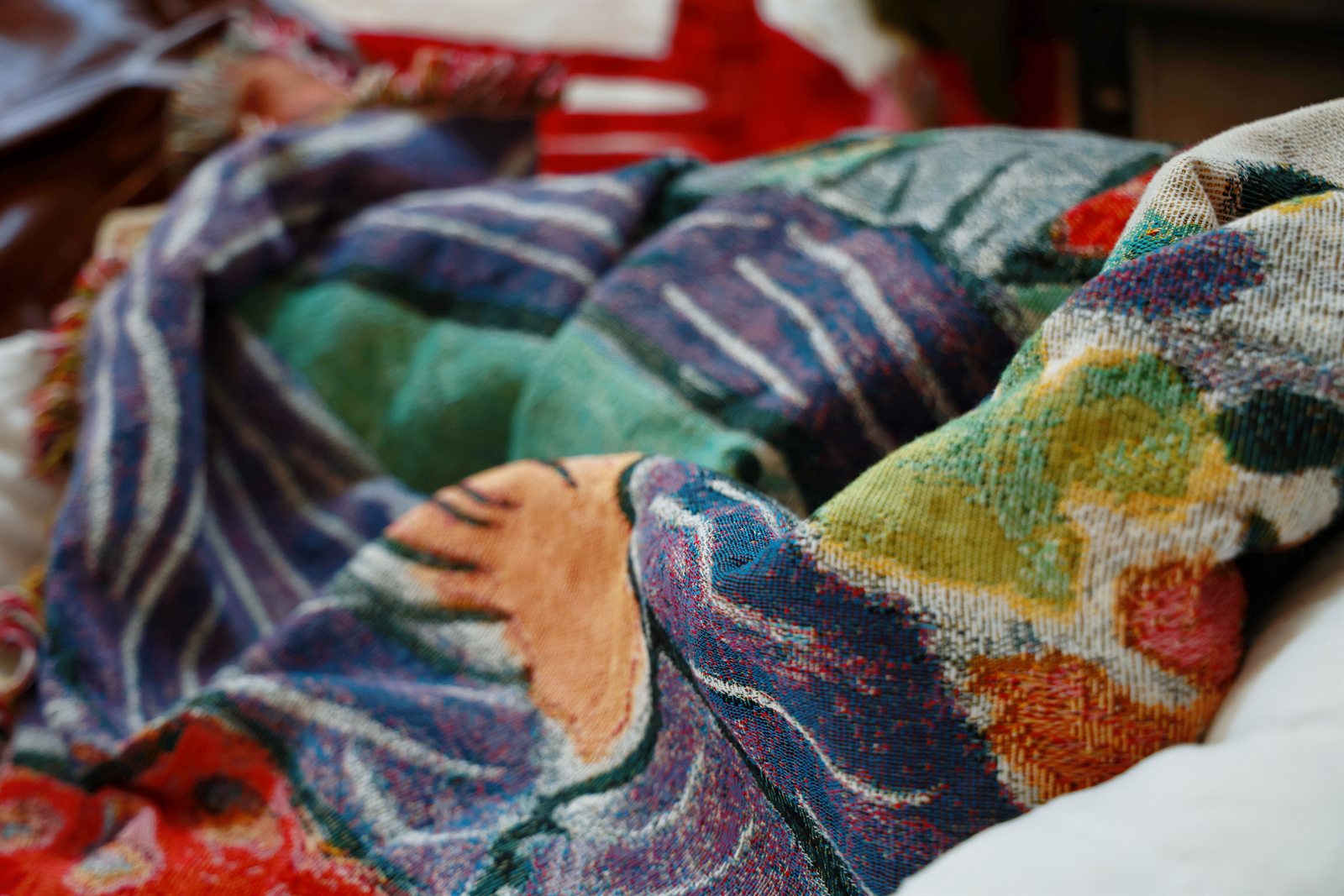 Close-up of colorful woven textile folds with a hand and painterly pattern details