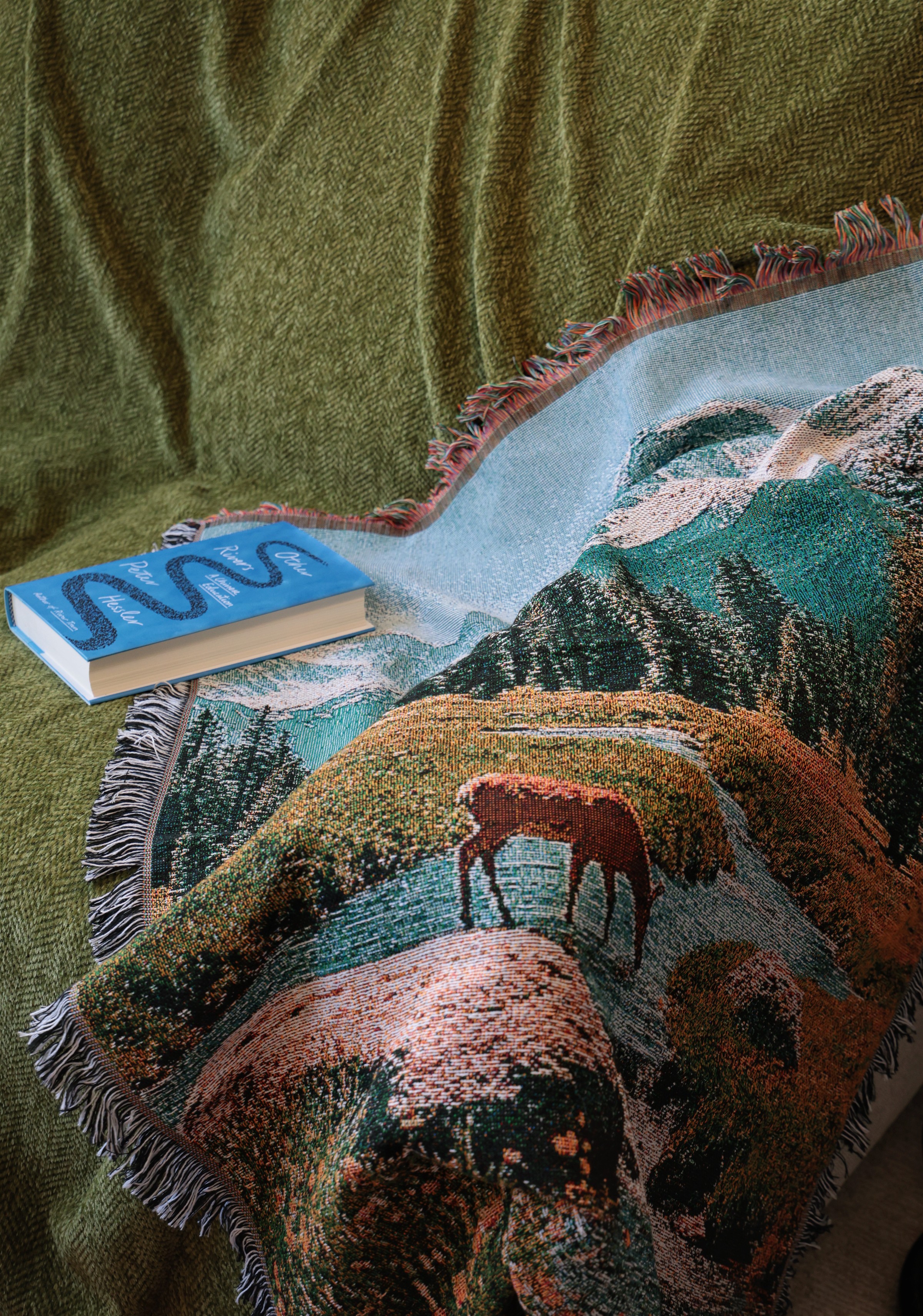 A patterned Loomoria textile draped across a green sofa beside a blue book